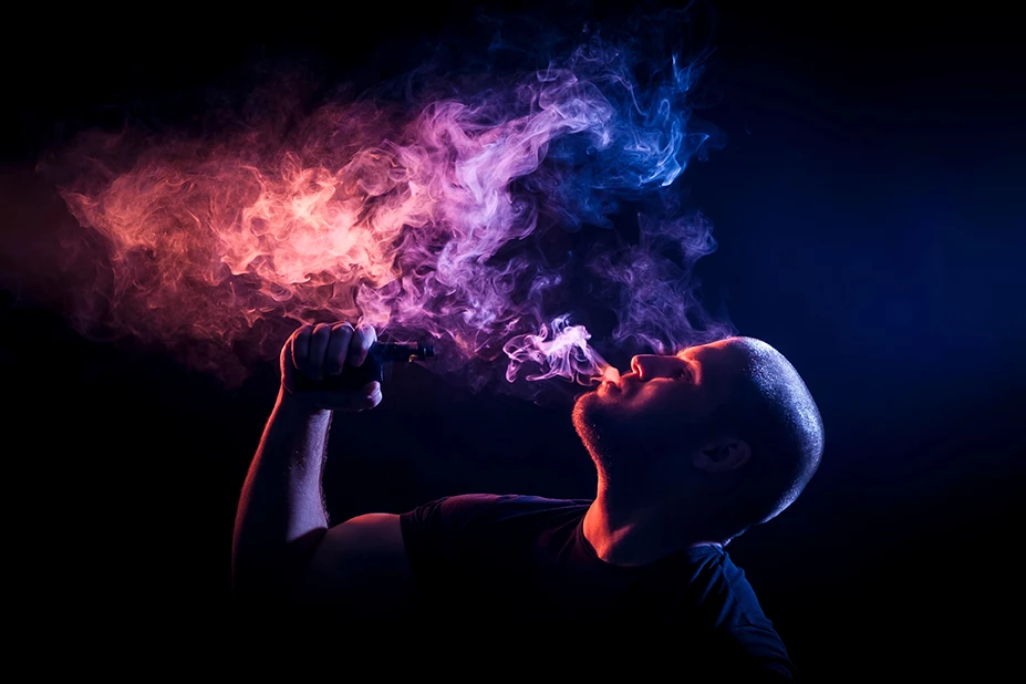 vape store Stevenson - man exhaling vibrant red and blue vape clouds
