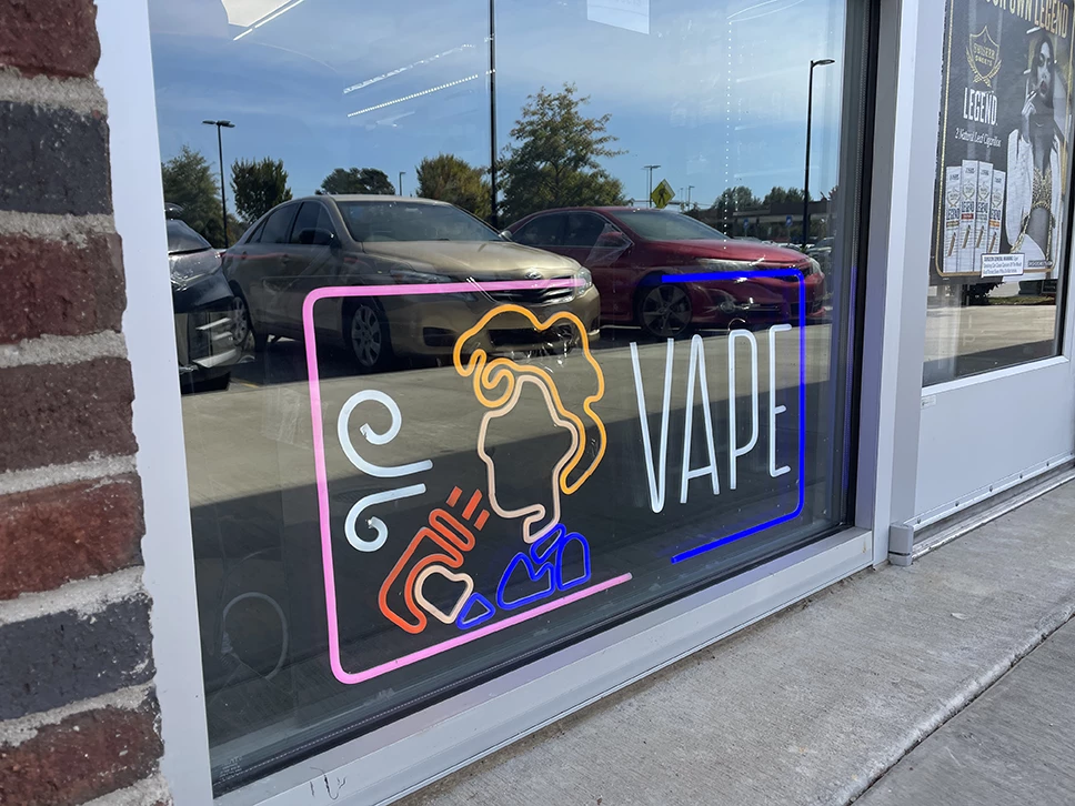 Exterior view of a vape and tobacco shop with a bright neon sign, Moeller Heights
