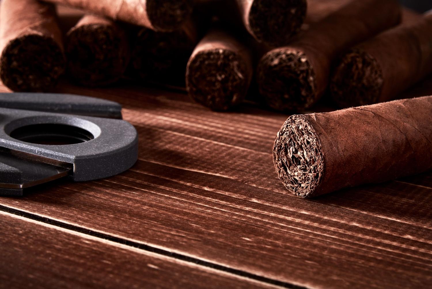 A premium cigar and cutter on a wooden surface, highlighting a cigar shop in Broken Arrow with a rich, warm ambiance.