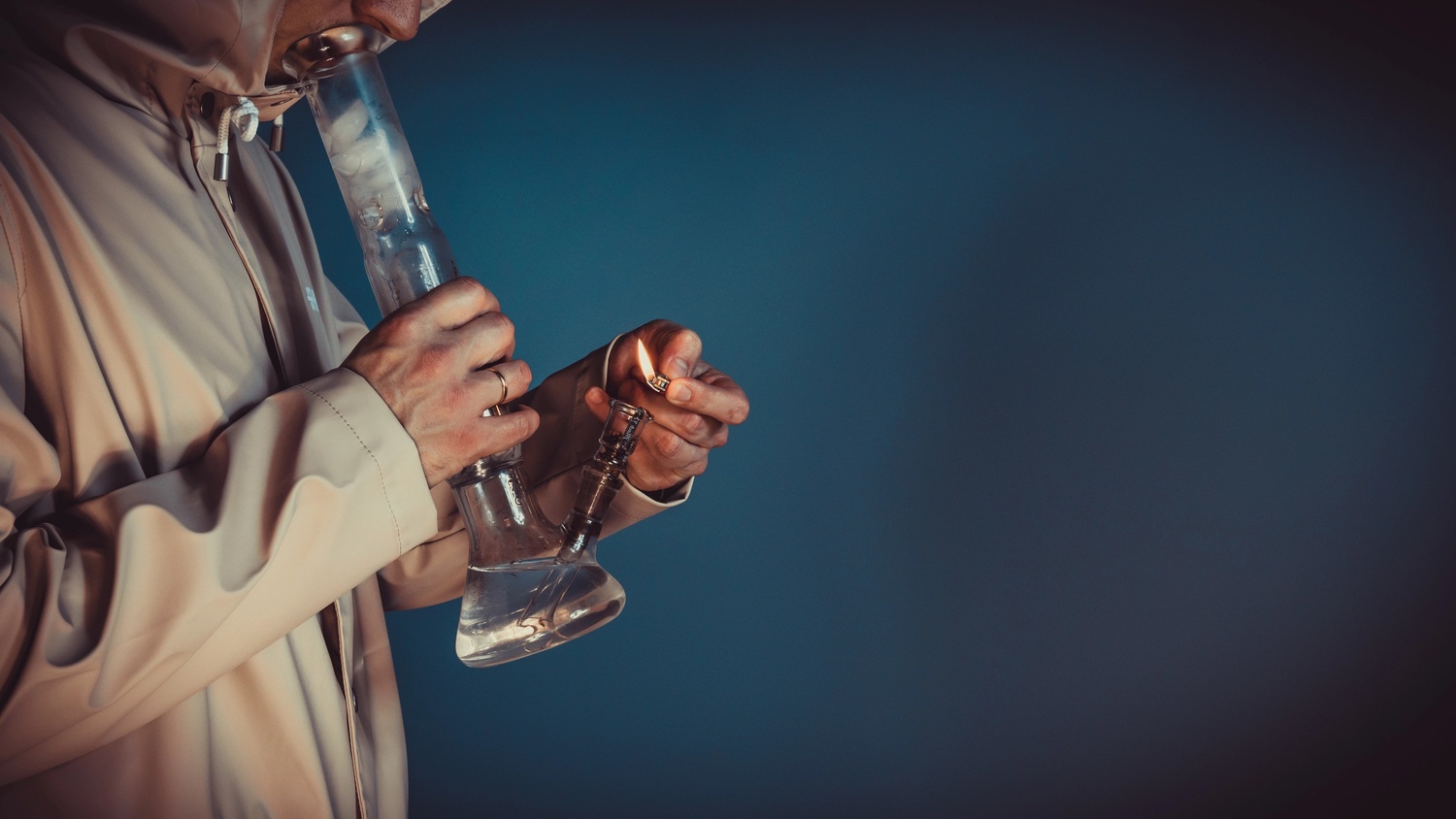 A person using a glass bong with a lighter, showcasing products from Head Shop Houston.