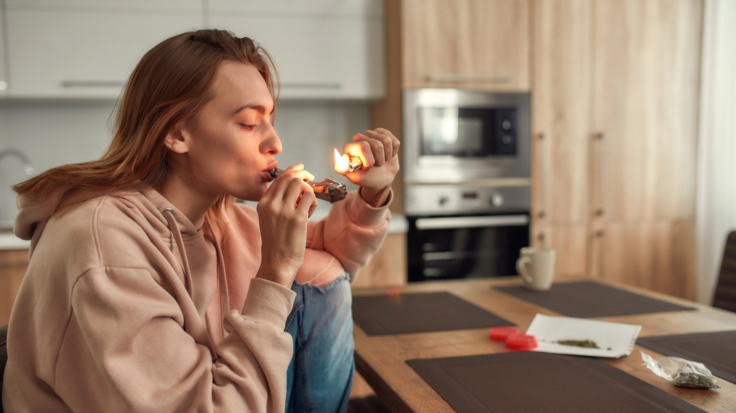 A person using a glass pipe in a kitchen, highlighting products from Head Shop Houston.