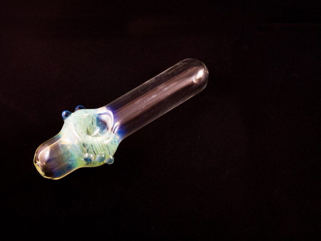 Vibrant handcrafted glass pipe with swirling green and blue hues, featuring intricate detailing and a unique design, available at Head Shop Houston.