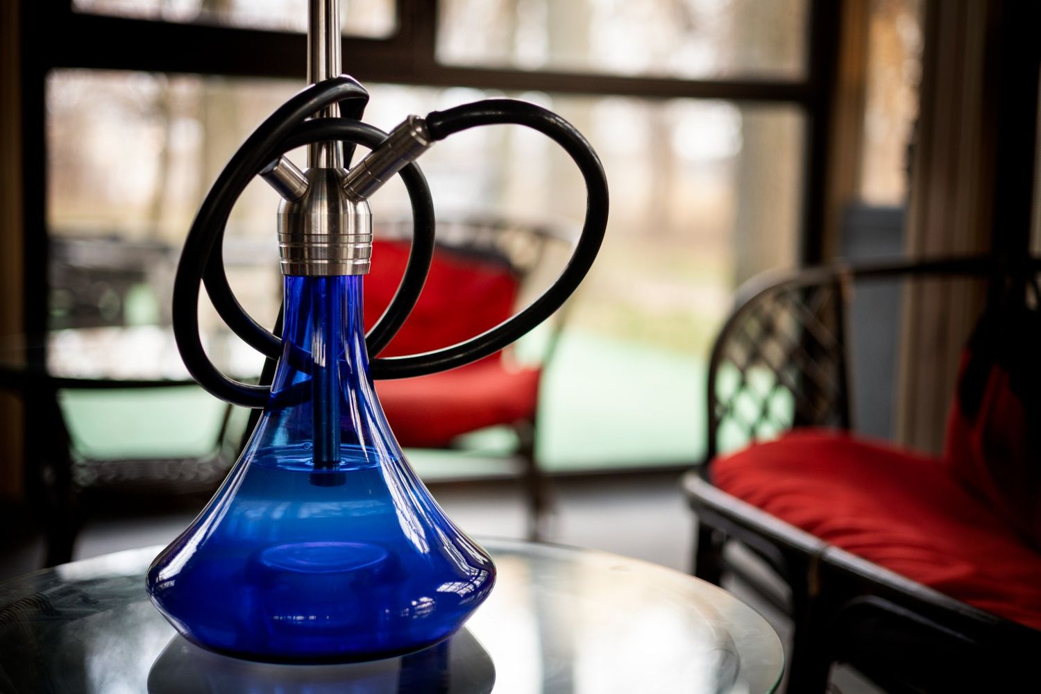 A blue hookah on a table with red chairs, offering a relaxing vibe at a hookah shop in Broken Arrow.