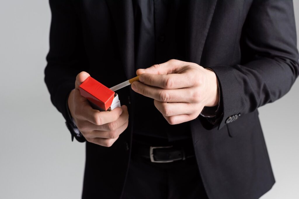 A person in a suit holding a cigarette pack, promoting a cigarette shop in Houston with a focus on tobacco products.