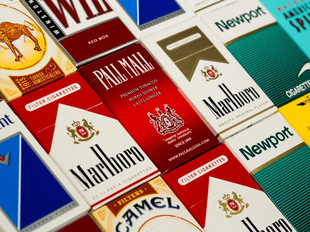 Shopper selecting cigarettes from a display at a cigarette shop in Houston with colorful packaging.
