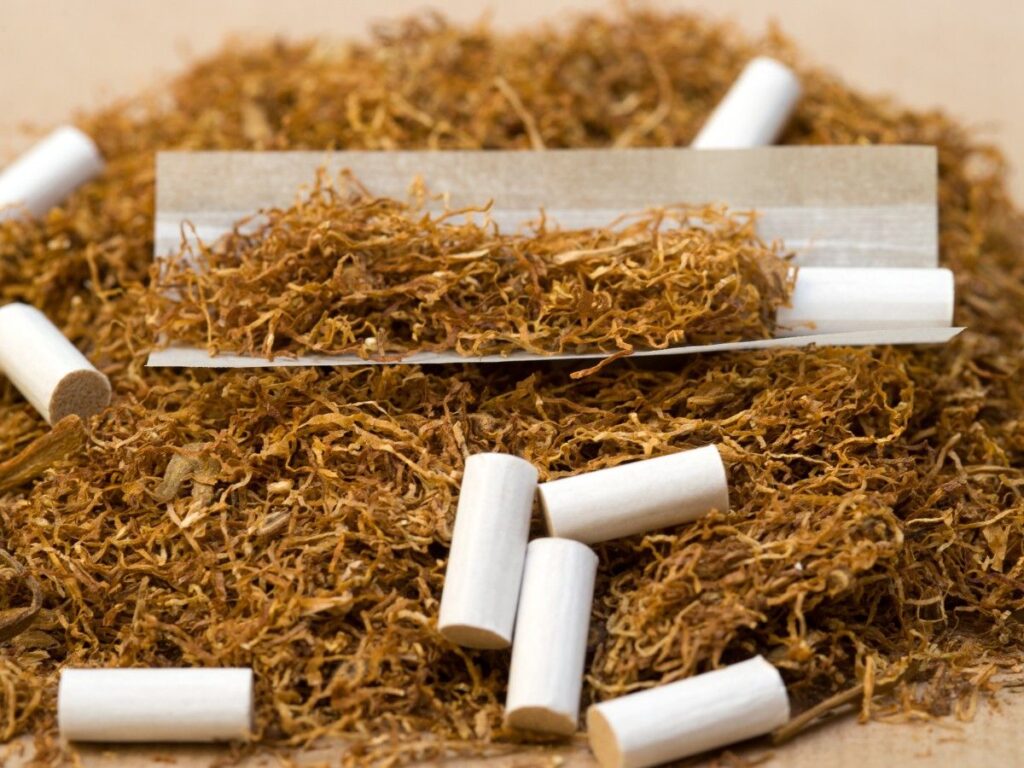 Close-up of Rolling Papers Houston with shredded tobacco and cigarette filters on a wooden surface