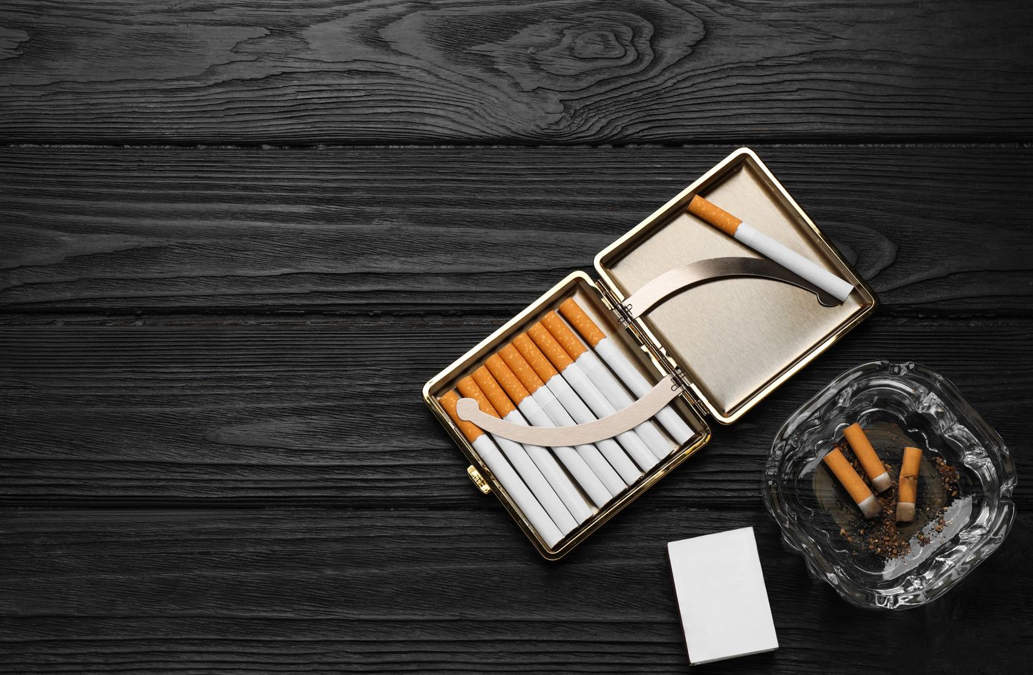 Open cigarette case with rolling papers and ashtray on dark wood, showcasing Rolling Papers Houston products for smokers.