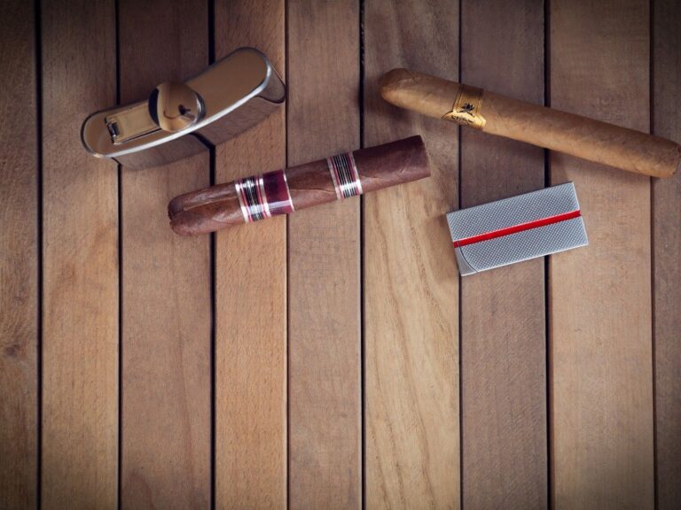 Premium cigars and smoking accessories displayed at Head Shop Houston, featuring a stylish silver cigar lighter with a classic design, placed on a warm wooden table alongside a finely crafted cigar with colorful bands.