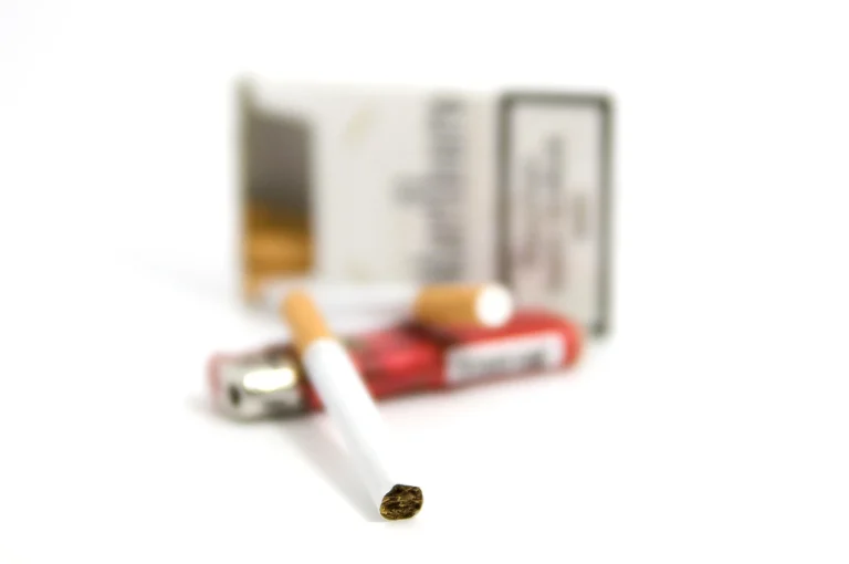 Close-up of lit and unlit cigarettes with packs and lighter at Cigarette Shop Broken Arrow.