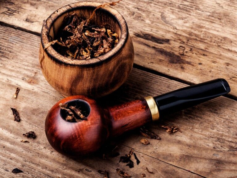 Rustic wooden table setting featuring a classic tobacco pipe with a golden band and a sturdy wooden bowl overflowing with rich tobacco blends, highlighting the authentic experience at Tobacco Shop Houston.