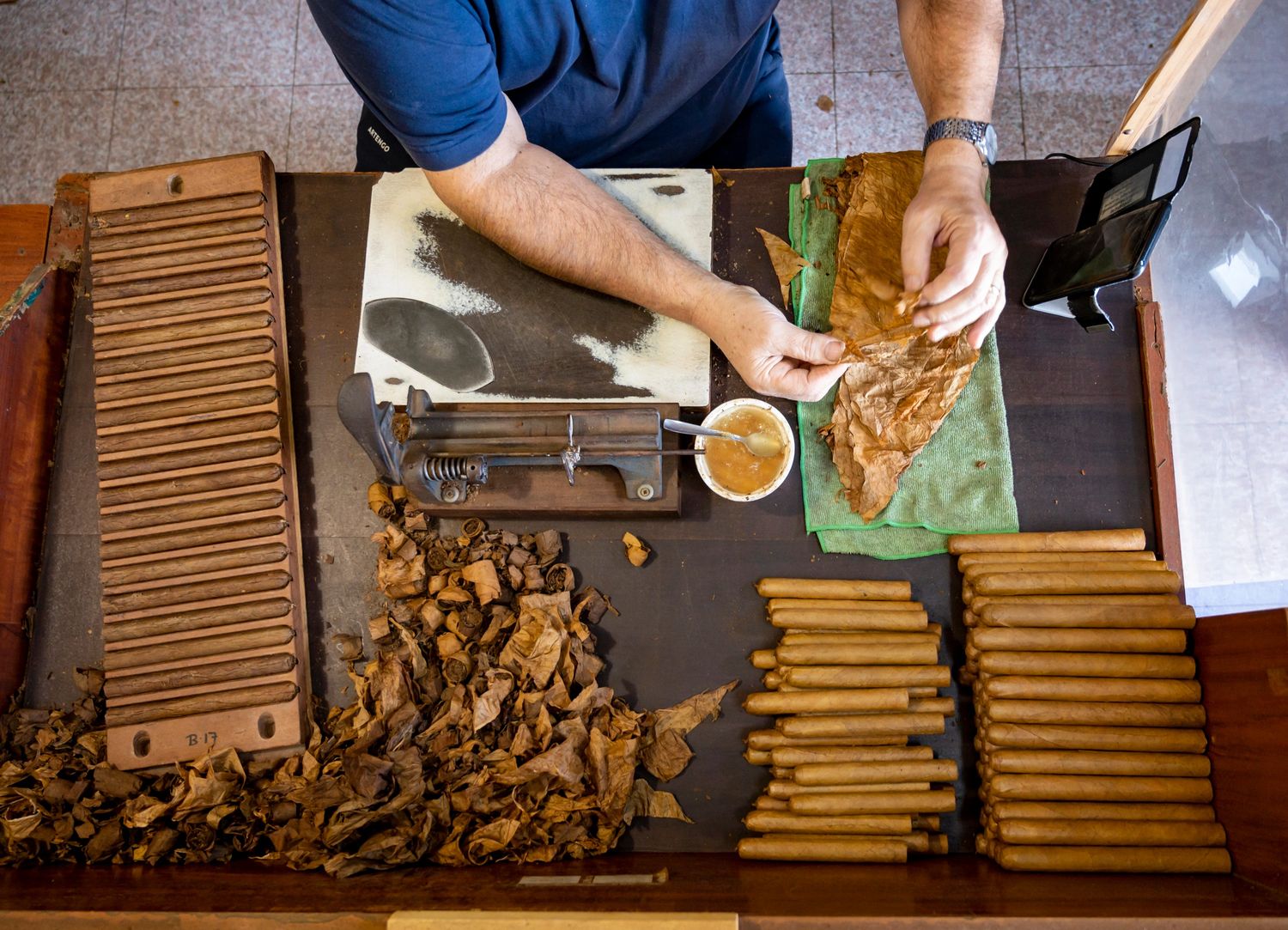 A person crafting cigars with tobacco leaves at Tobacco Shop Houston, showcasing traditional methods.