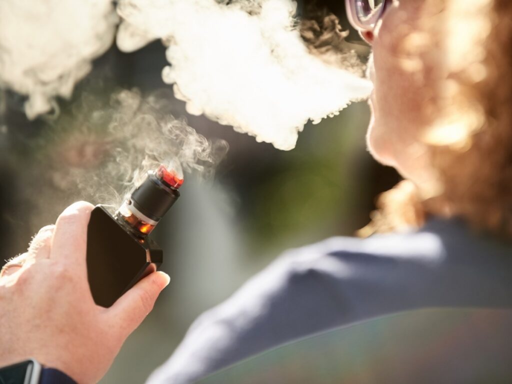 Individual enjoying a vape session with a high-quality device from Vape Shop Houston, captured in a natural setting.