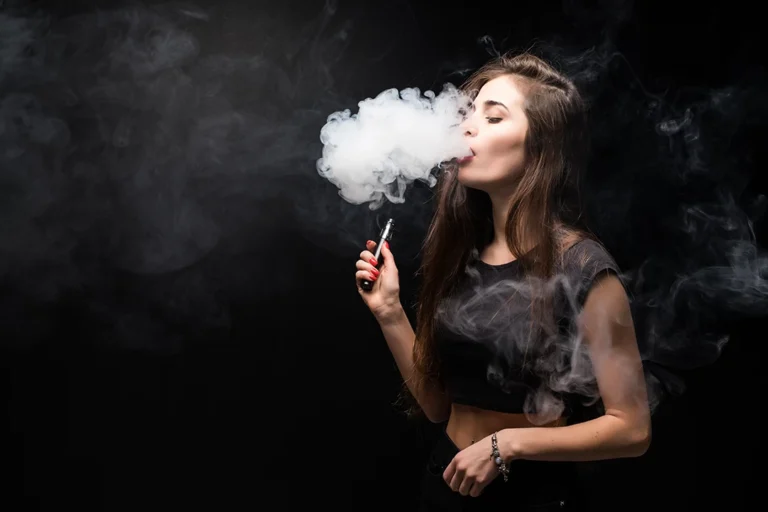 Woman vaping with thick clouds against a dark backdrop, showcasing a trendy Vape Shop Houston vibe.