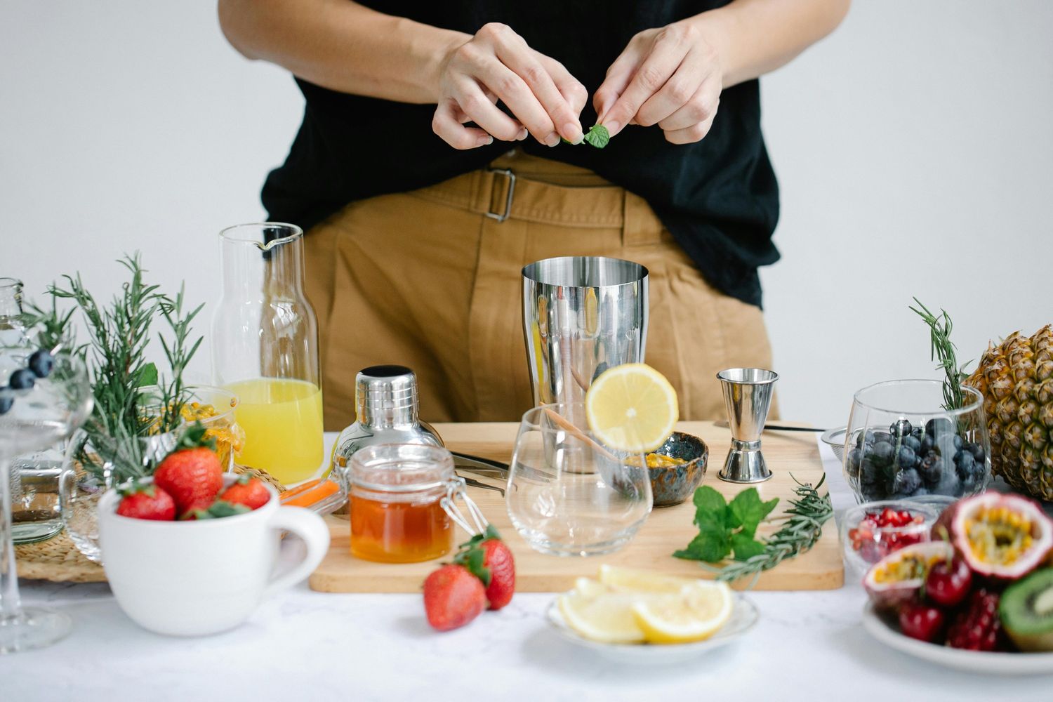 A person preparing a drink with fruits and herbs at Vape Shop Houston, featuring a vibrant cocktail setup.