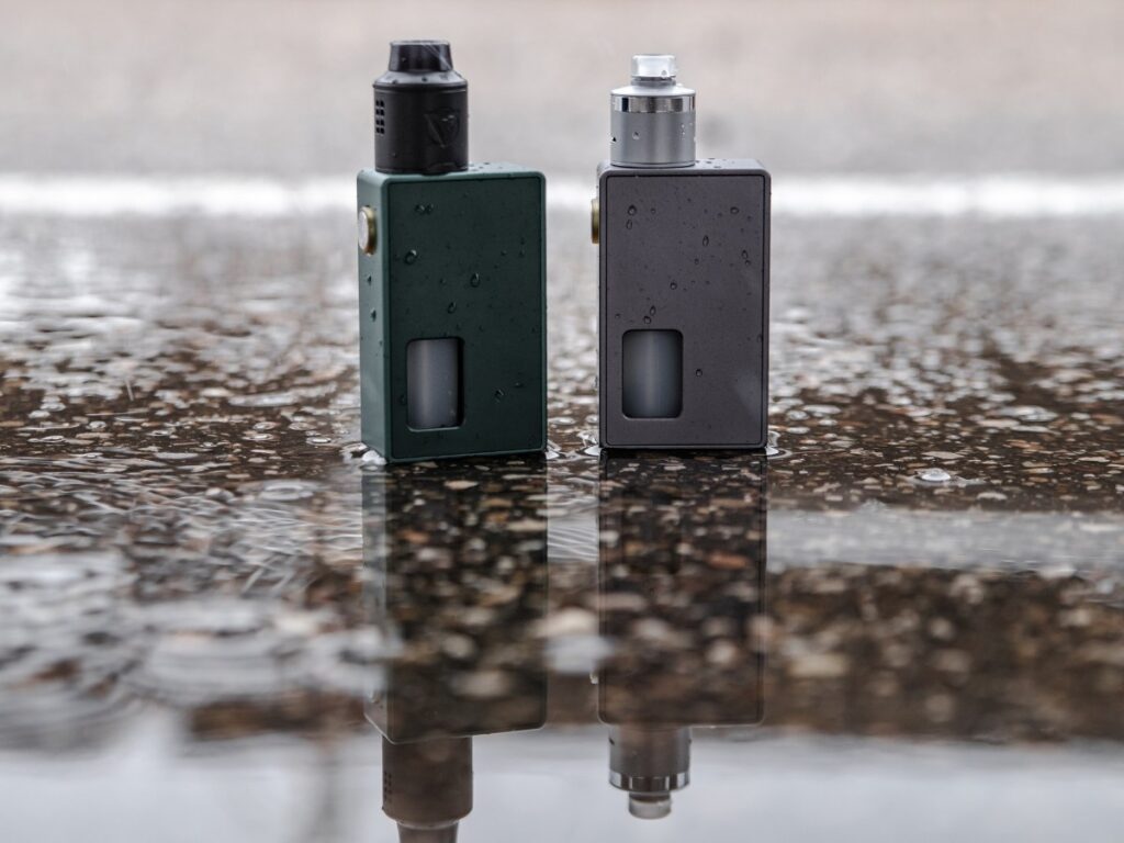 High-quality vape mods in green and gray from Vape Store Houston, showcased on a reflective wet background.
