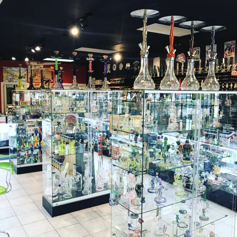 Colorful hookahs and glass pipes displayed in glass cases at a busy Head Shop Houston.