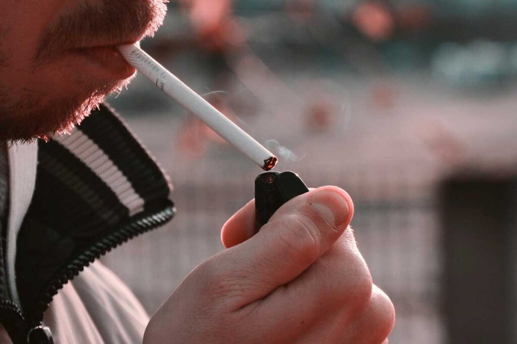 Close-up of a person lighting a cigarette outdoors with a lighter, find accessories at your local smoke shop broken arrow.