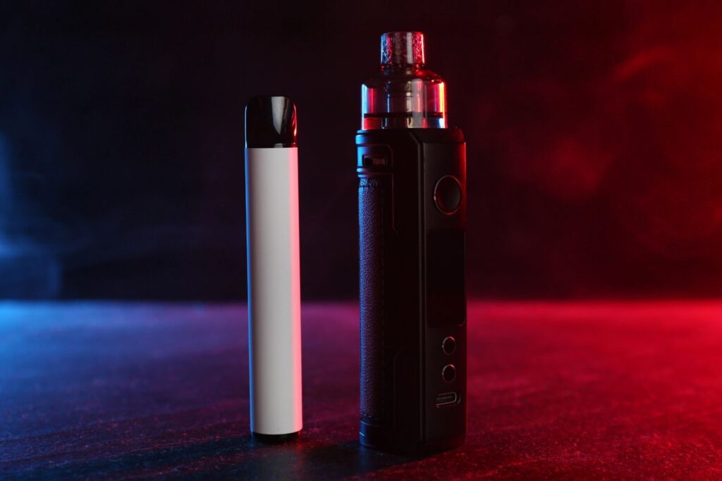 Two modern vape devices displayed with vibrant lighting at a vape store in Houston, showcasing variety.