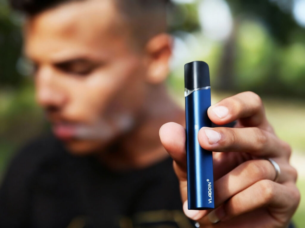 Man holding a sleek blue vape device outdoors at the premier head shop in Broken Arrow, showcasing stylish vaping options for modern users.