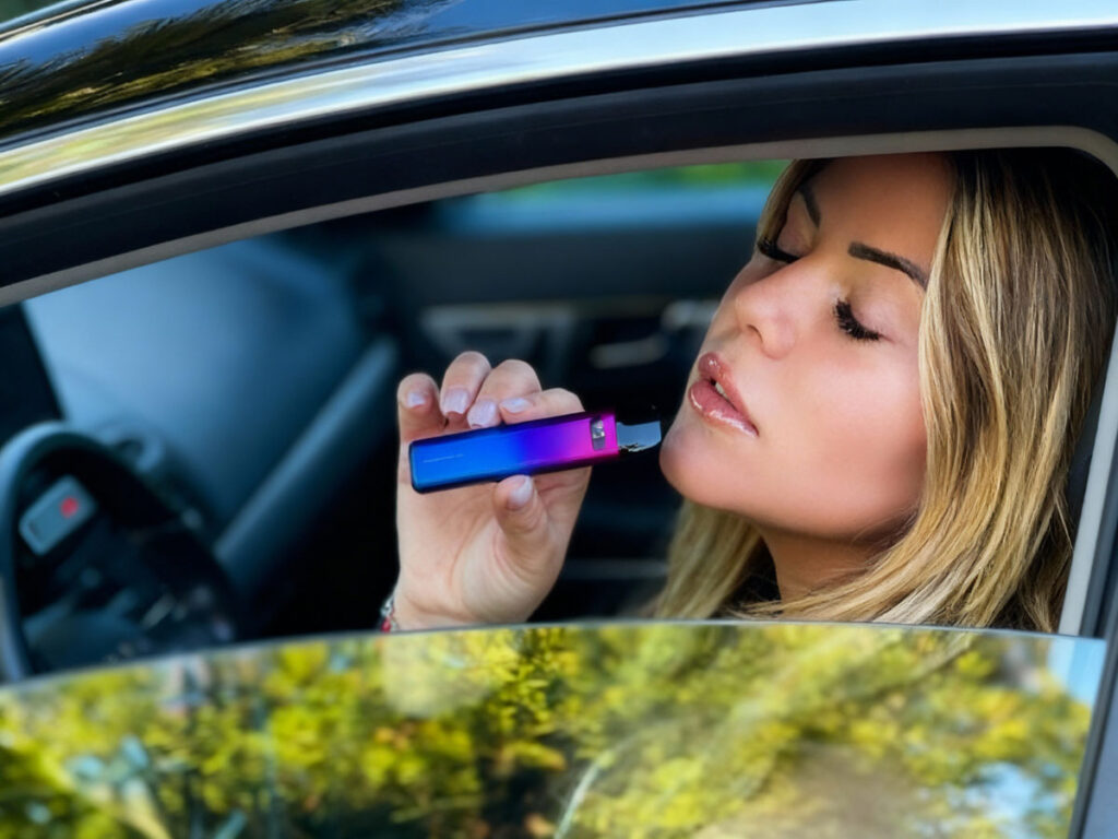 Woman using a colorful vape inside a car at the leading head shop in Broken Arrow, highlighting premium vaping gear for a unique experience.