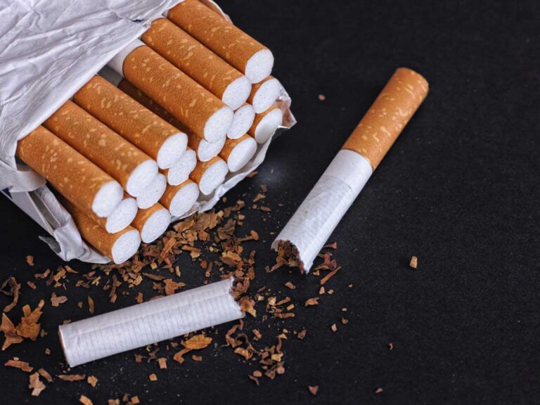 Close-up of an open pack of cigarettes with loose tobacco spills at a tobacco store in Broken Arrow, showcasing premium smoking products for discerning customers.