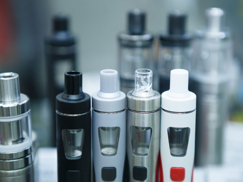 Close-up of diverse vape devices on display at a trendy vape shop in Tulsa, showcasing different styles and designs for vapers.