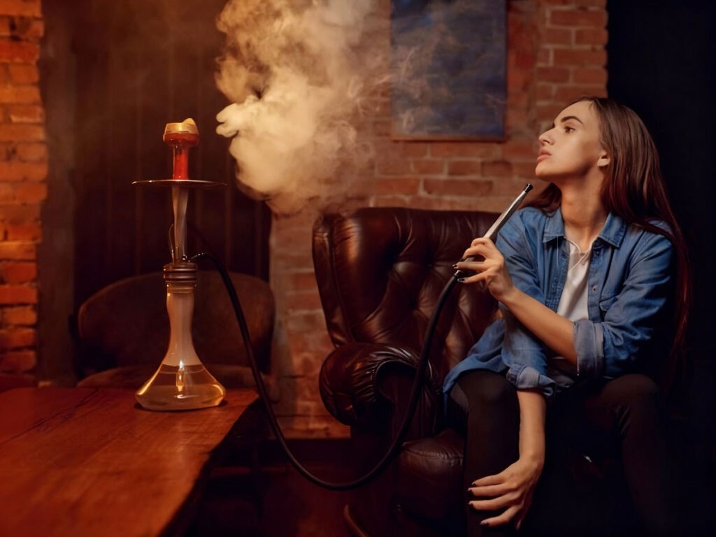 Woman lounging in a comfy chair at a trendy hookah shop in Tulsa, savoring a smooth hookah experience with elegant decor.