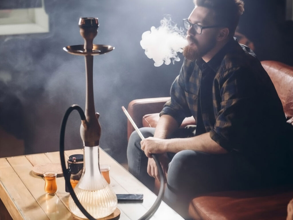 Guy relaxing with a hookah at a welcoming hookah shop in Tulsa, surrounded by warm lighting and a laid-back atmosphere.