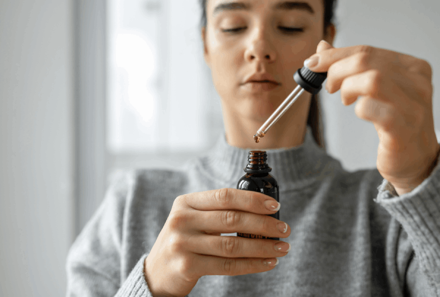 Person using CBD oil dropper—experience natural relief and wellness from trusted products at a CBD shop in Owasso.