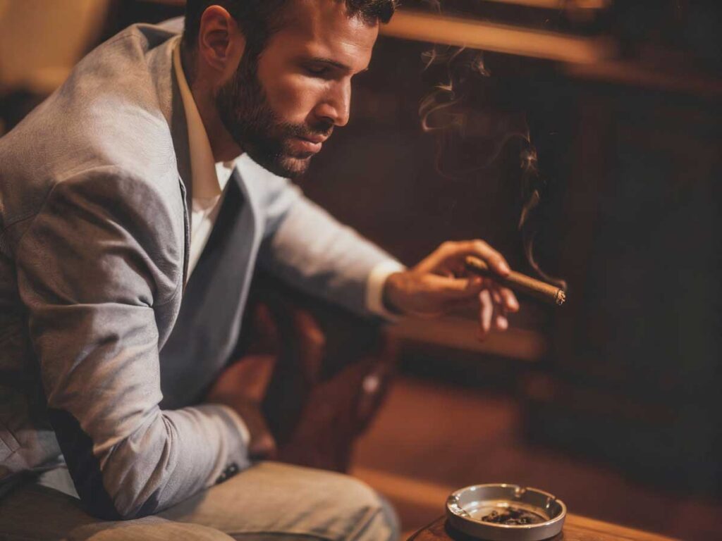 Gentleman enjoying a fine cigar at a sophisticated tobacco shop in Broken Arrow, with smooth smoke adding to the relaxed ambiance.