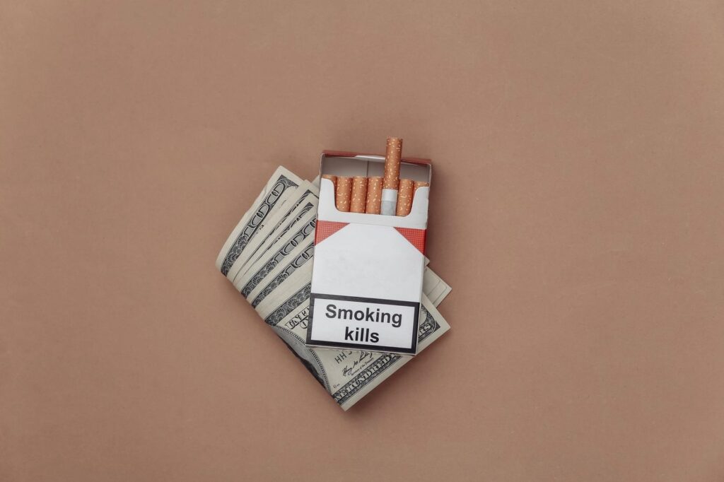 Cigarette pack on dollar bills with “Smoking kills” label—explore pricing and brands at a leading cigarette shop in Tulsa.