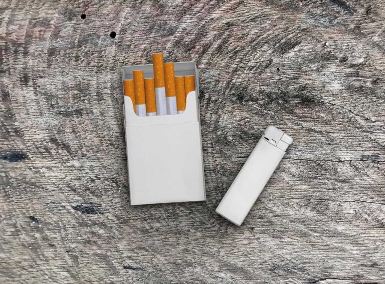 Cigarette pack and white lighter on a wooden surface from top-rated Cigarette Shop Houston.