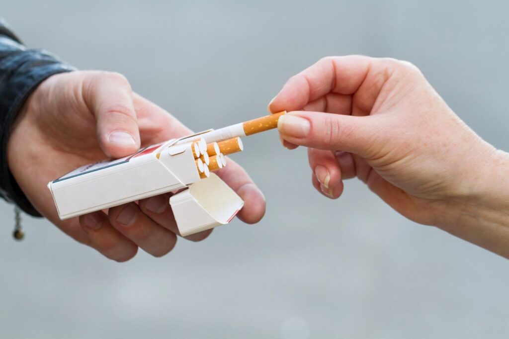 Close-up of hands pulling a cigarette—find your preferred brand at the leading cigarette shop in Tulsa.