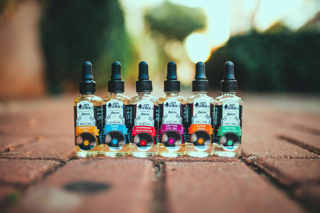 Variety of popular e-liquids and gourmet Vape Juice Tulsa flavors, including "Perfect Day," lined up on an outdoor brick patio.