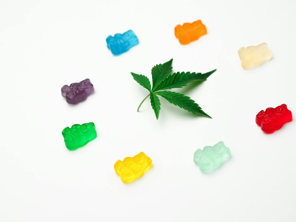 Colorful, delicious CBD gummy bears surrounding a hemp leaf. Find the best selection at a reliable CBD Store Tulsa location.