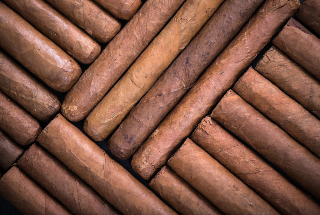 Artful arrangement of many hand-rolled, natural brown cigars showcasing the expansive inventory at a leading cigar shop Houston.