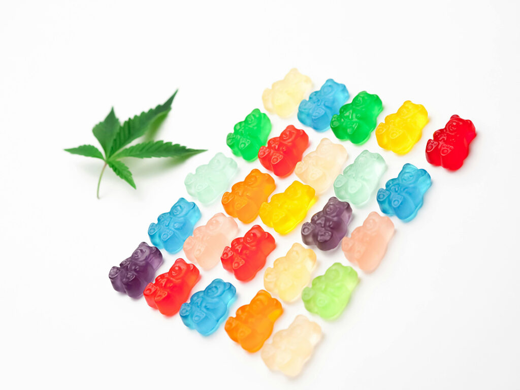 A neat arrangement of multicolored CBD gummy bears and a hemp leaf. Shop top-rated edibles at your local CBD Store Tulsa.