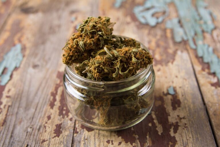 Close up of high quality hemp flower buds in a clear jar on a rustic table from our local delta 8 store owasso shop.