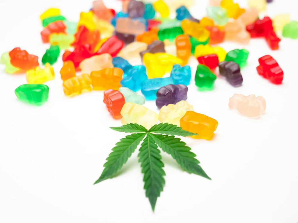 Pile of colorful CBD gummy bears and a hemp leaf ready for tasting. Find the best local CBD Store Tulsa deals and reviews.