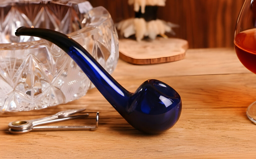 Cobalt blue Sherlock glass pipes Houston style on a wood table with a crystal ashtray and classic smoking accessories.