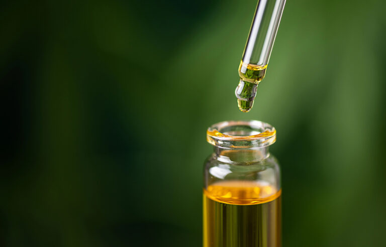 Golden CBD oil dropper releasing a pure droplet into a glass bottle, highlighting premium quality products at CBD shop in Broken Arrow.