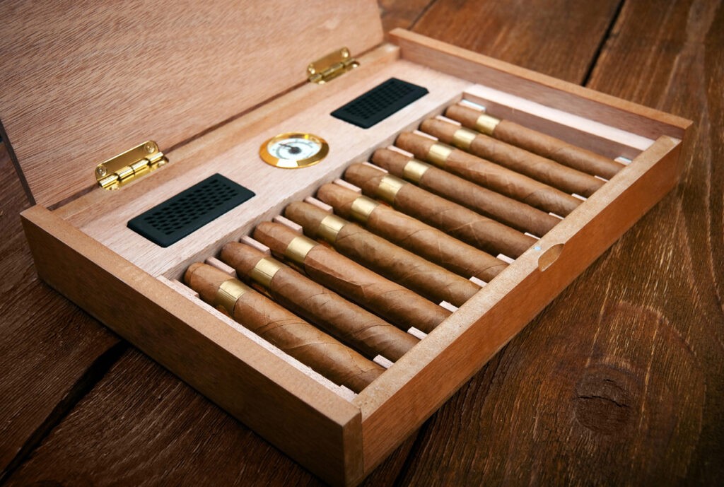 Open wooden humidor displaying a row of eight golden-banded cigars, a vital accessory from a top cigar shop Houston.