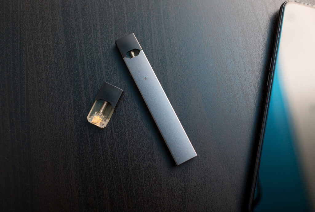 Detailed close-up of a high-end black vape device and replacement pod on a dark background. See our stock at a vape shop Houston.