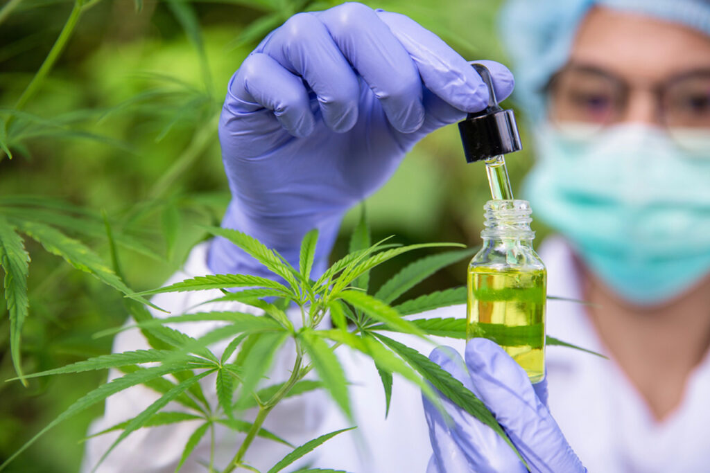 Lab technician in protective gear carefully extracting CBD oil near cannabis plants, showcasing purity at Broken Arrow's trusted CBD shop.