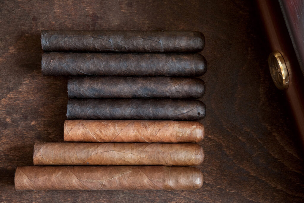 Premium dark and light tobacco leaf cigars inside a luxury wooden humidor at a top-rated cigar shop Owasso location.