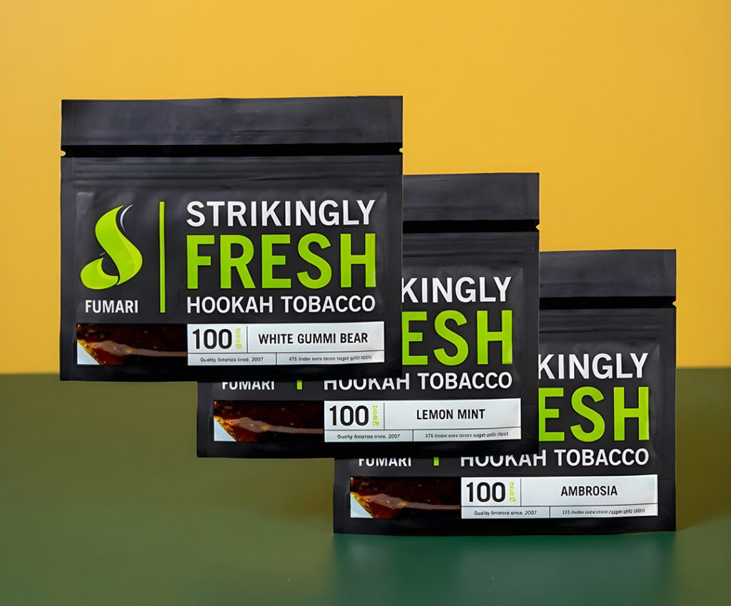 Fumari hookah tobacco pouches including Ambrosia flavor on a wooden table in a lounge at this shisha store tulsa.