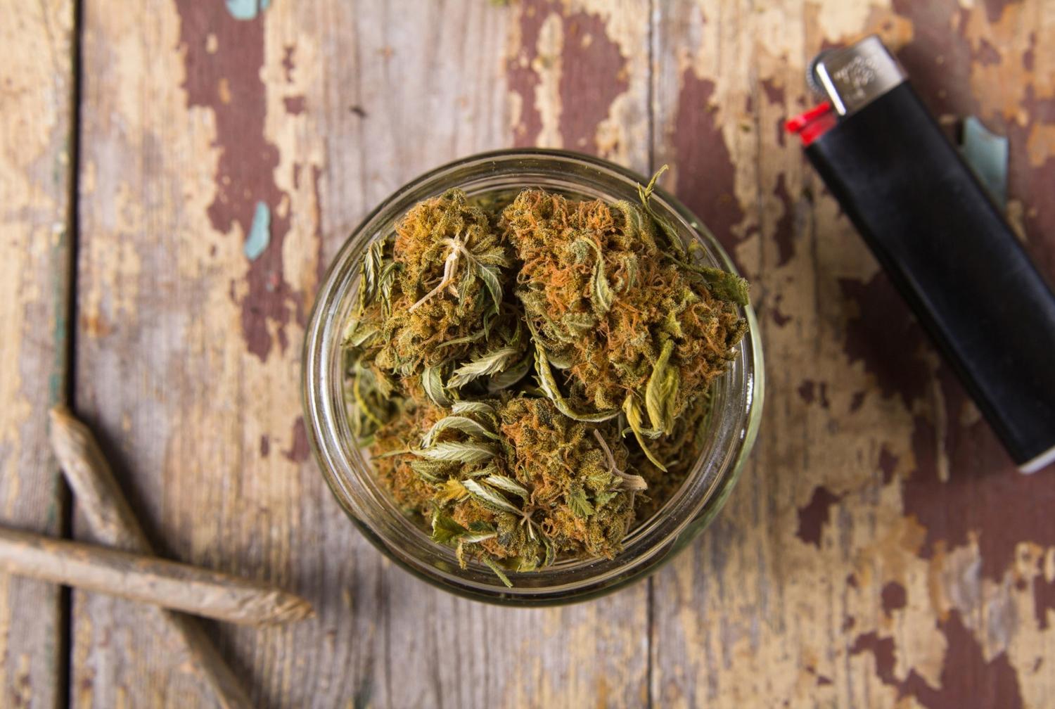 Premium cannabis flower in a glass jar with a lighter and pre-rolls, available at our delta 8 store owasso location.