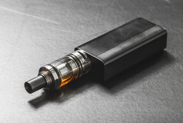 Close-up of a high-performance black box mod with a glass tank and amber juice from a specialized Vape Store Tulsa.