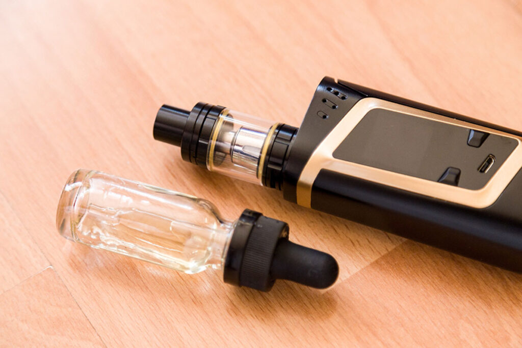 Premium box mod kit and e-liquid bottle with dropper on a wood surface, available at your local Vape Store Tulsa shop.