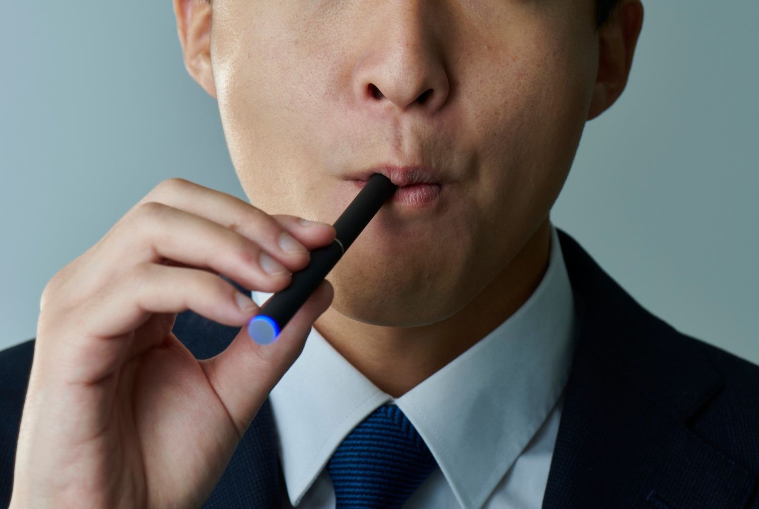 A man in a suit using a sleek black vape pen purchased from a top-rated E-cigarettes Tulsa shop near me.